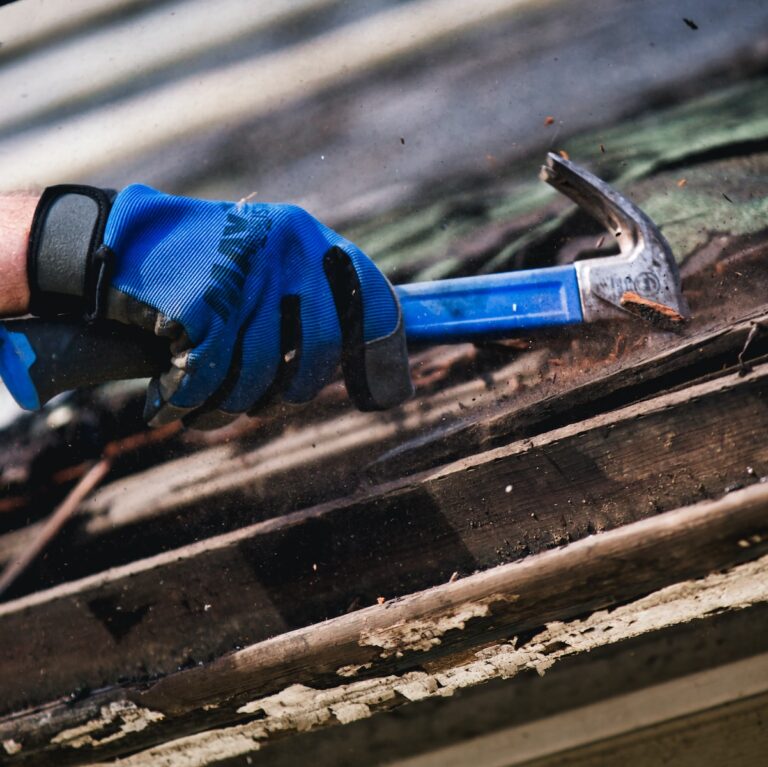a person wearing blue gloves and holding a hammer